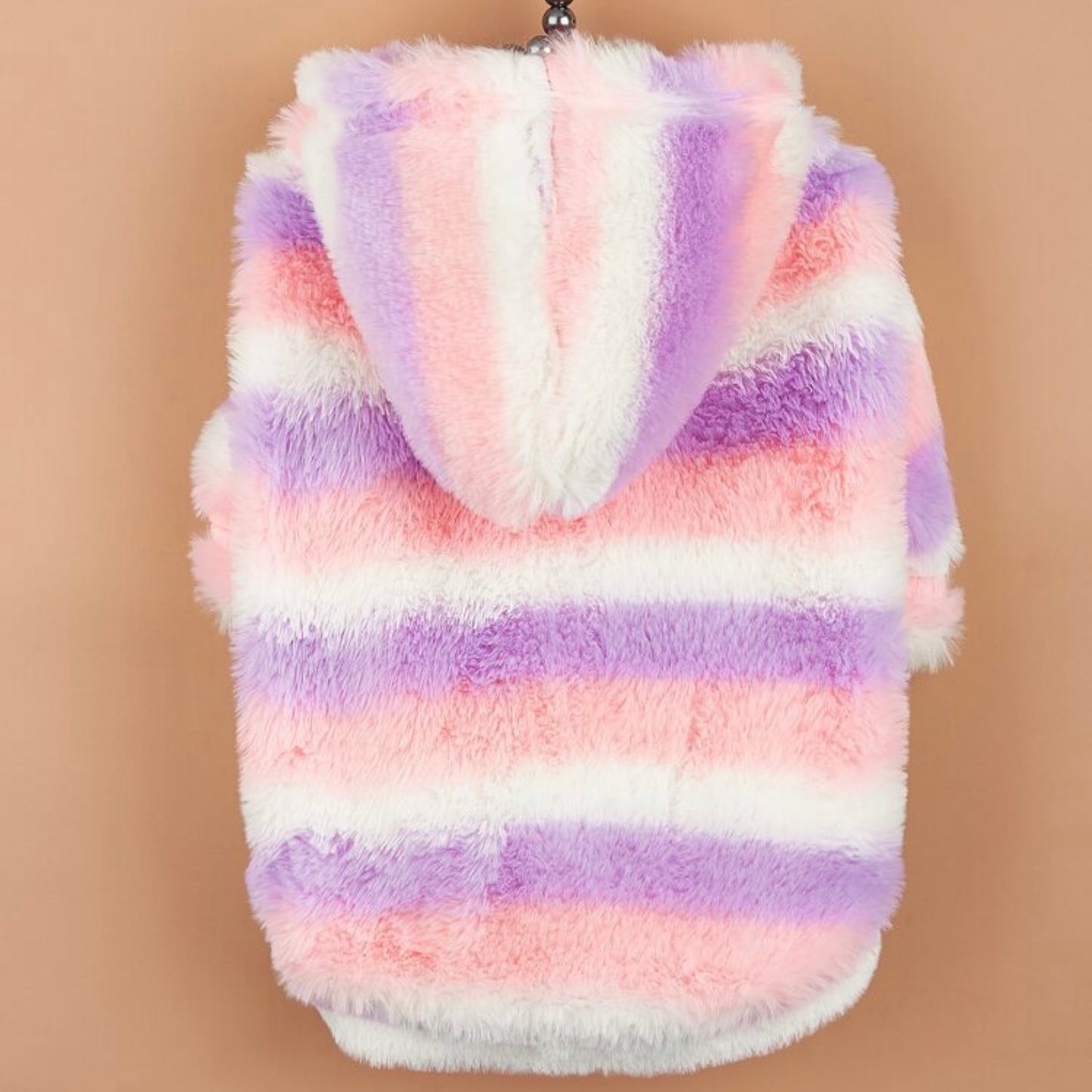 Back view of a pastel striped fluffy dog jacket with a hood, hanging on a hanger against a tan background.