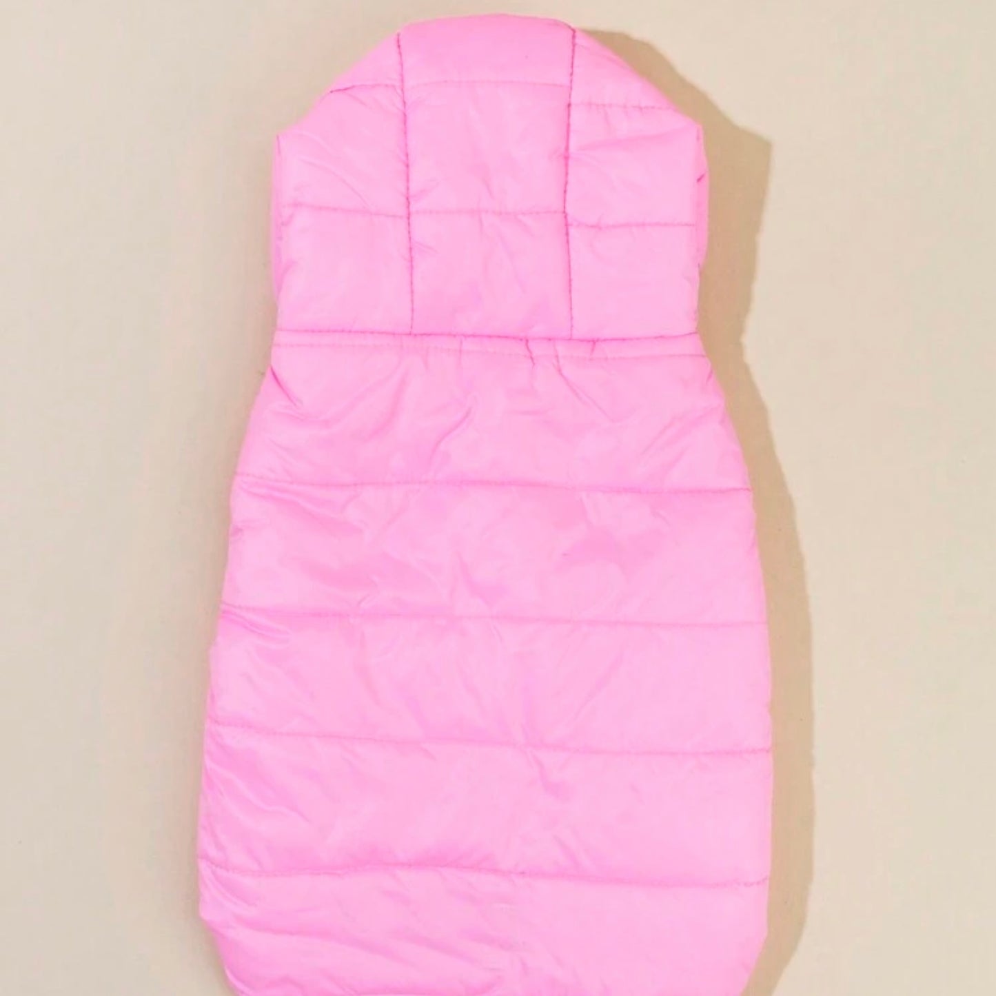 A light pink puffer dog jacket with a hood, laid flat to show the back and overall shape.