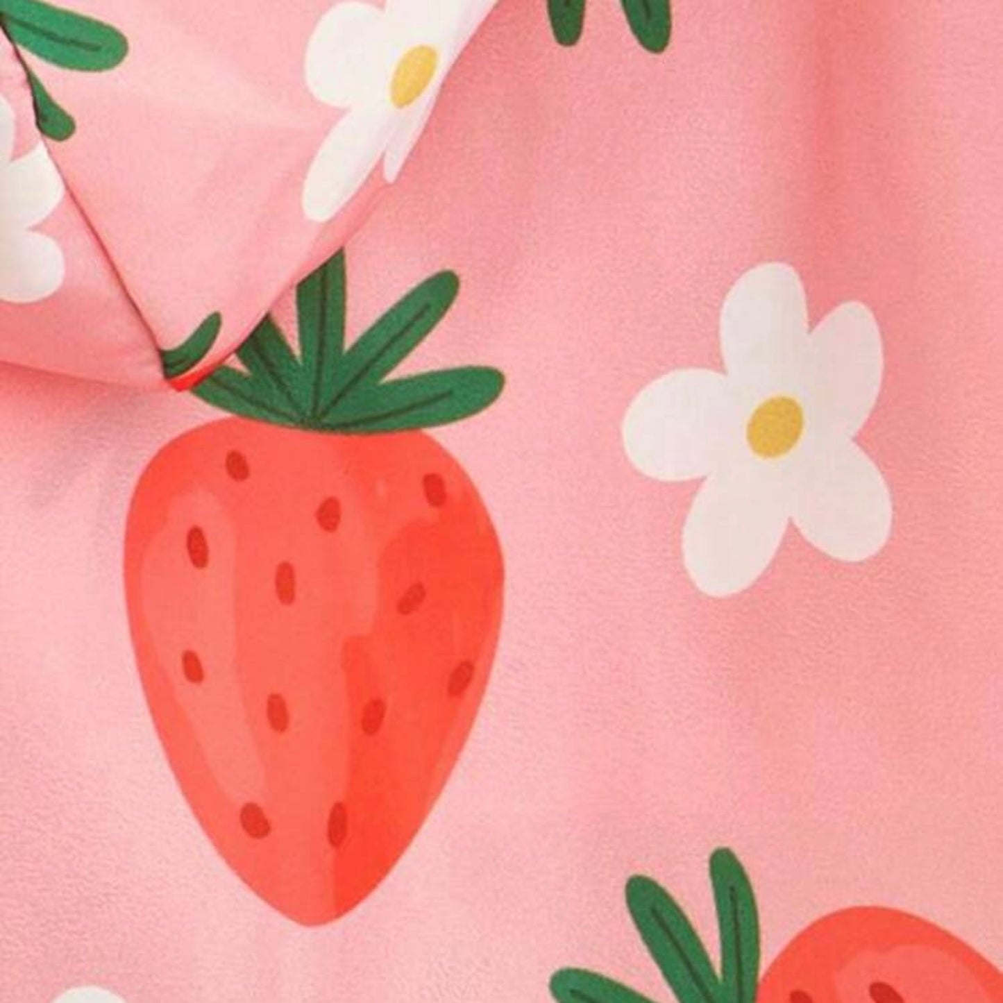 Close-up of a pink raincoat fabric featuring a red strawberry and white flower print.
