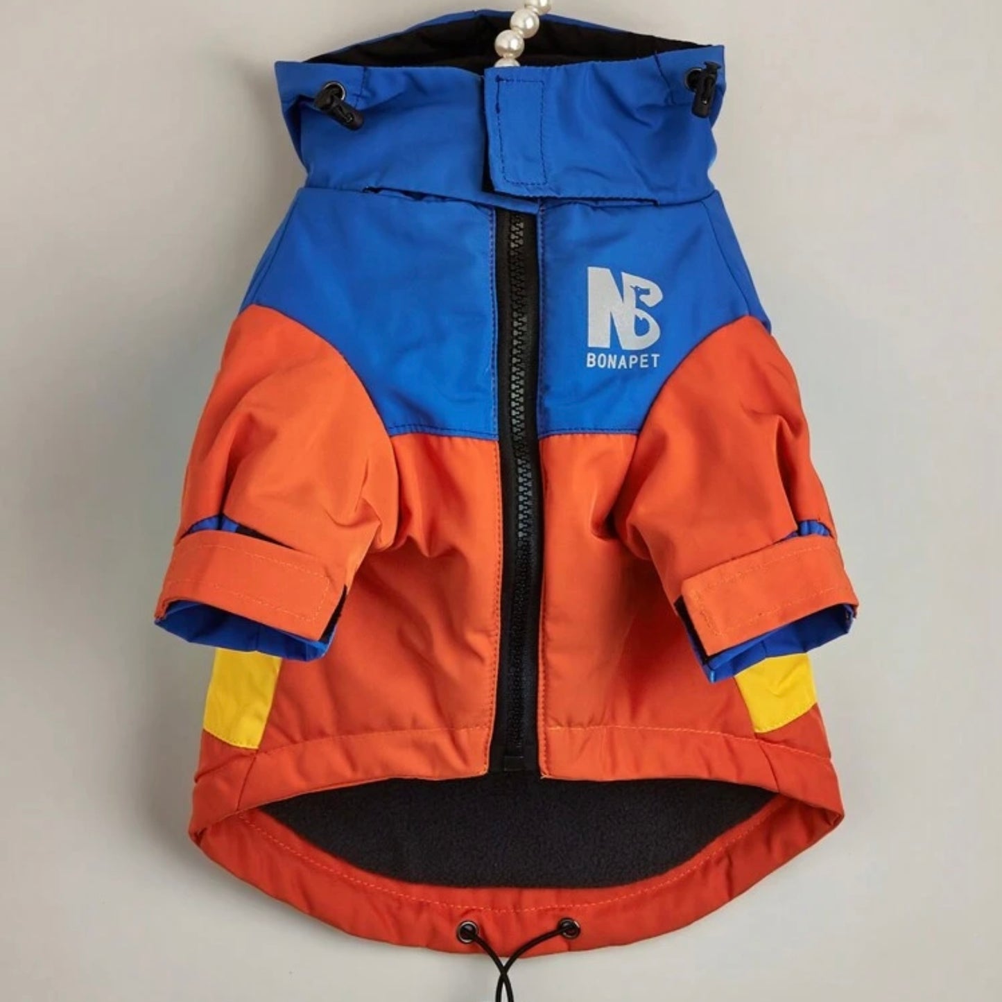 Colourblock dog jacket in blue, yellow, and red displayed on a hanger, front view.