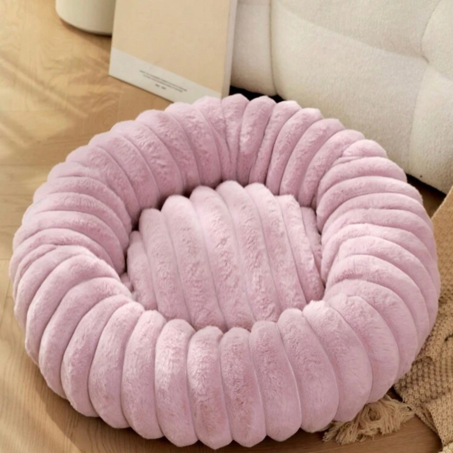 Plush ribbed donut dog bed in lilac placed indoors.