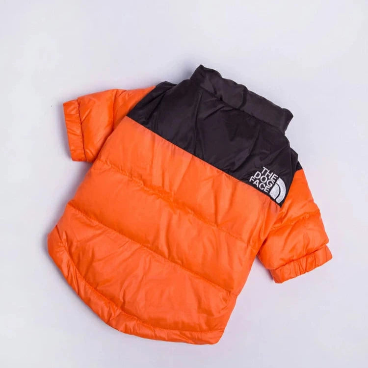 Orange and black puffer dog jacket laid flat on a white background, featuring "The Dog Face" logo on the shoulder.