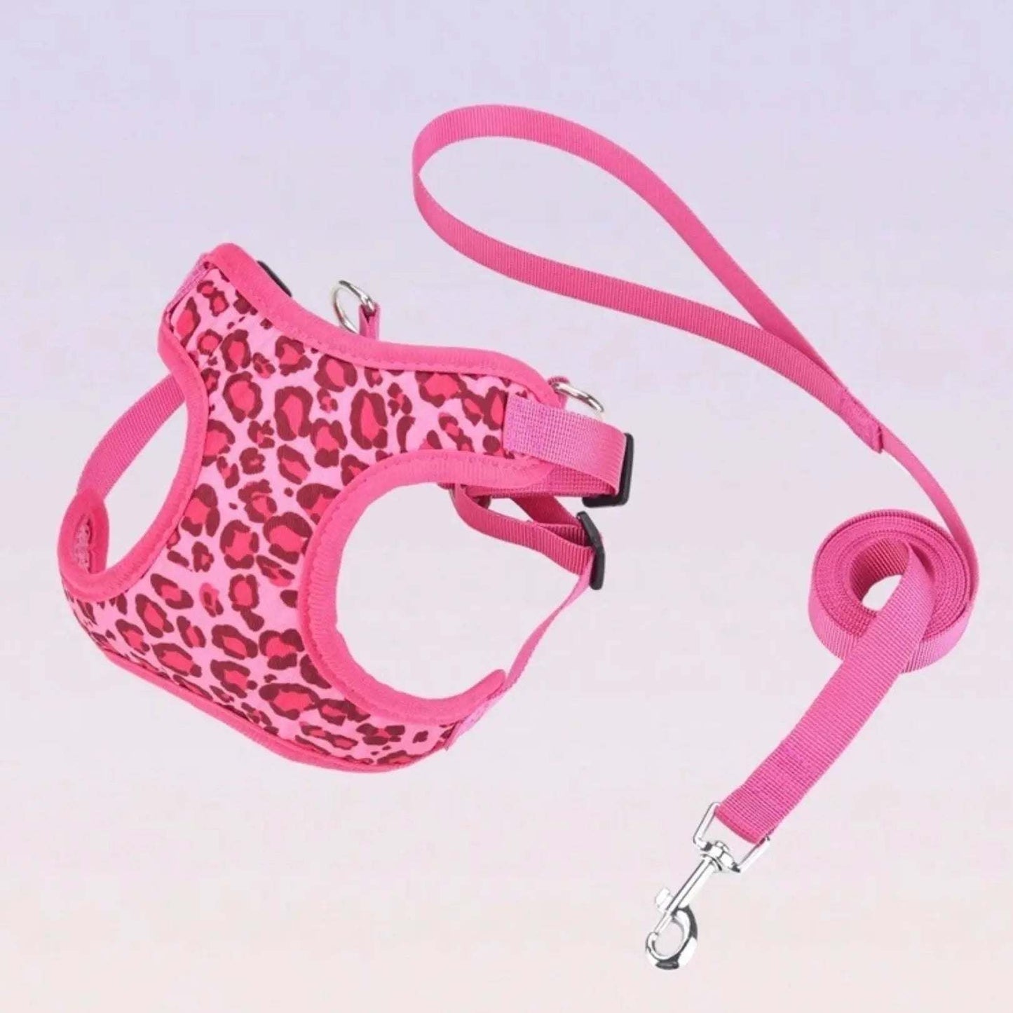 Pink leopard print dog harness and matching pink leash set on a light background.