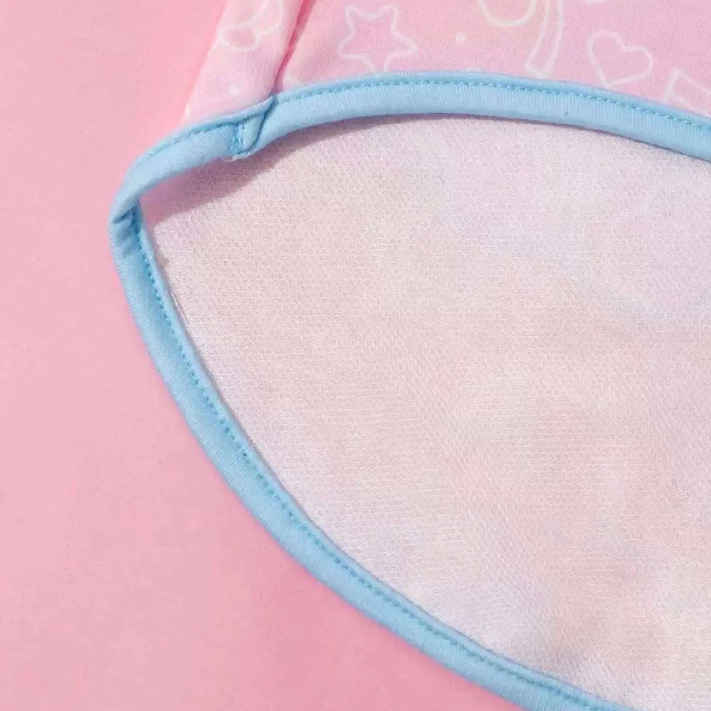 Close-up of the armhole and blue trim on a pink Care Bears dog tank top with subtle heart and star patterns.