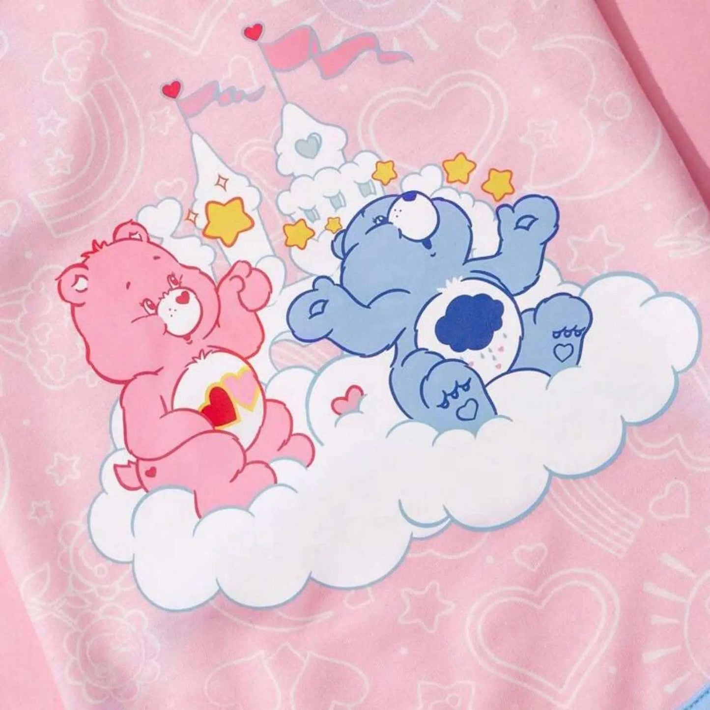 Close-up of Care Bears graphic on pink dog top, showing a pink bear and a blue bear sitting on a cloud with stars and hearts in the background.