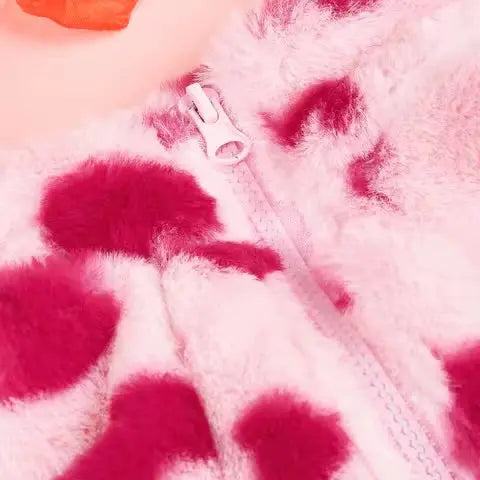 Close-up of a pink heart print faux fur dog jacket with a white zipper.