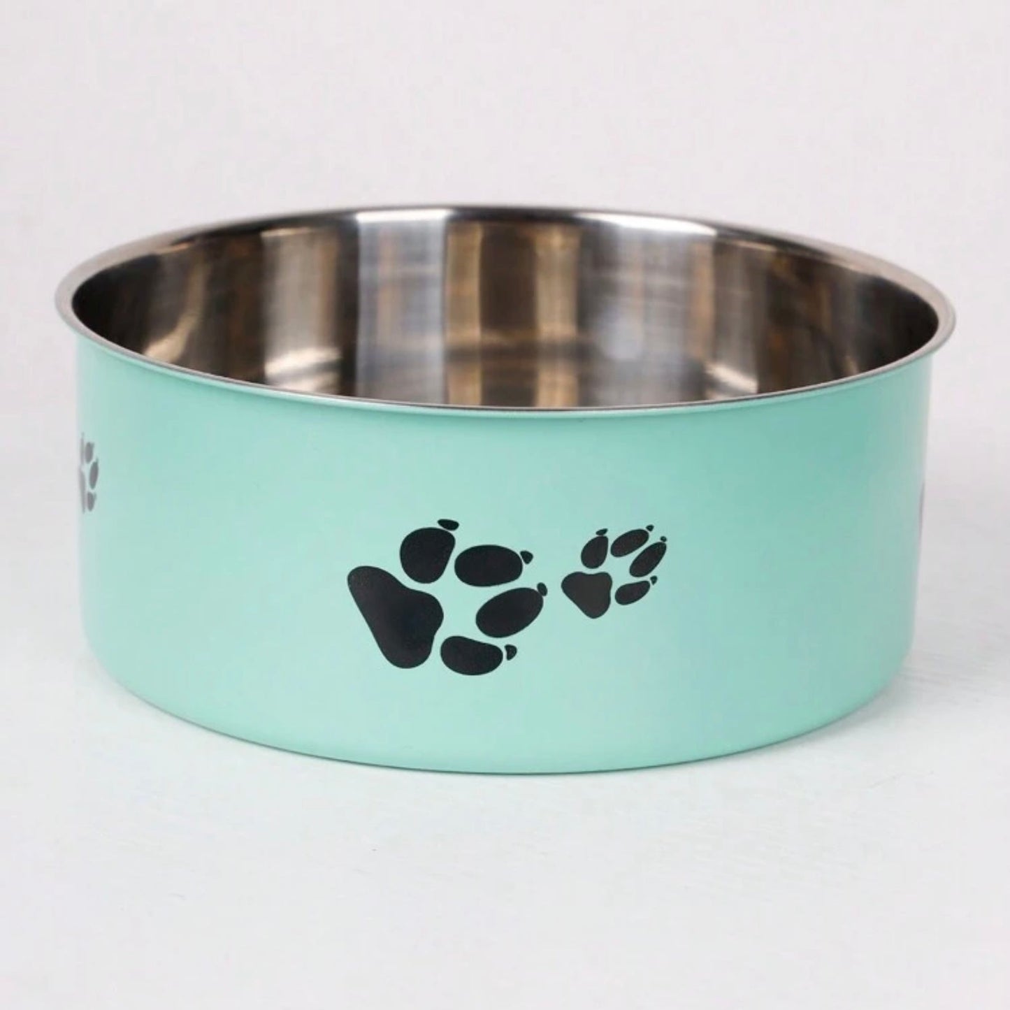 Mint green stainless steel pet bowl with black paw prints on the side, empty and placed on a white background.