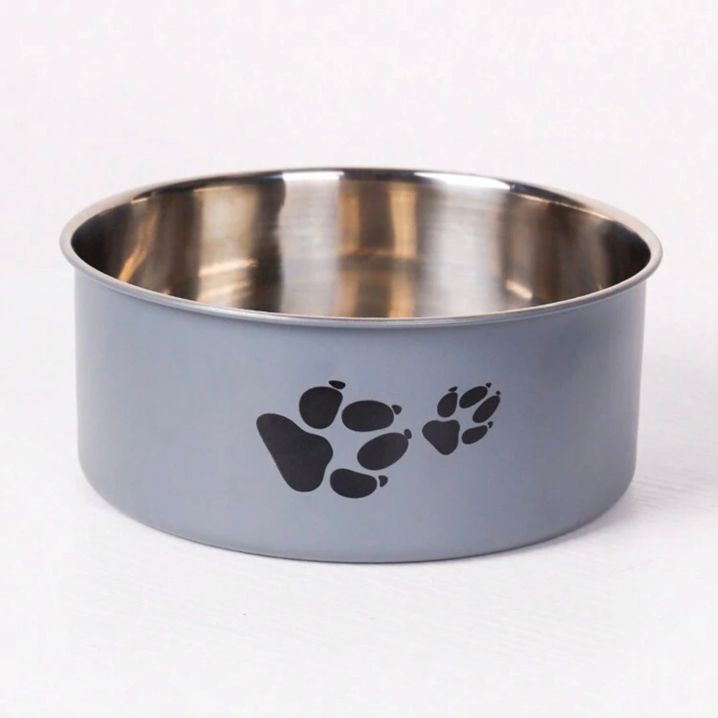 Gray stainless steel dog bowl with black paw prints on the side, empty and placed on a white surface.