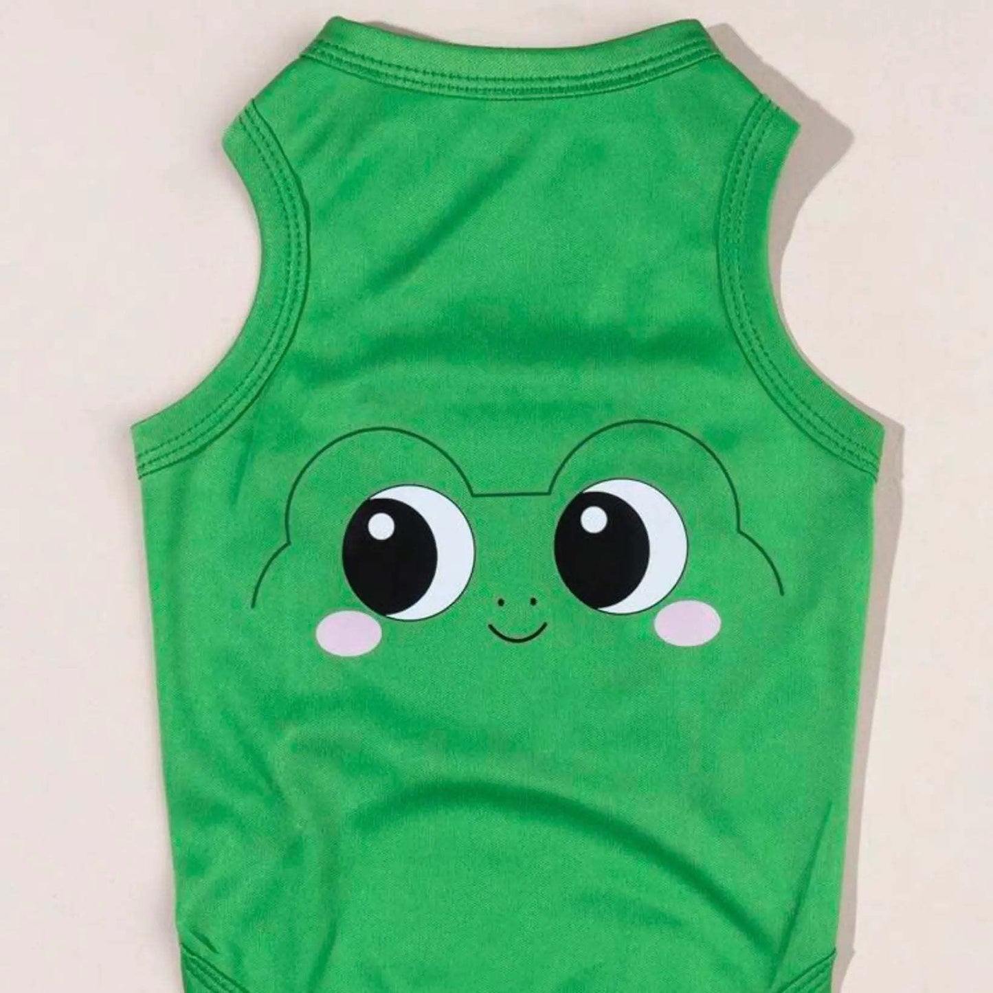 Green dog shirt with a cartoon frog face design laid flat on a surface.