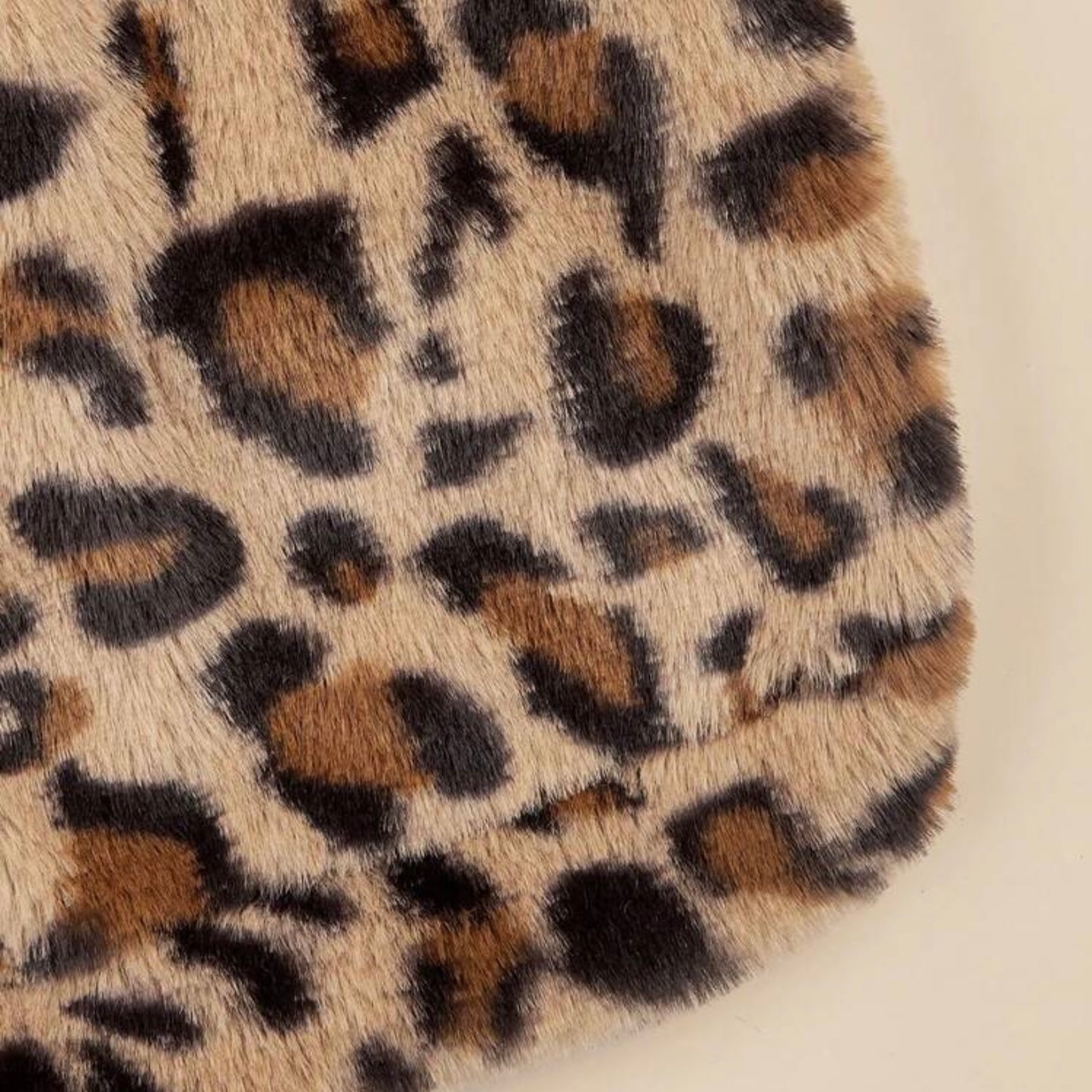 Close-up detail of the soft faux fur leopard print fabric of a dog hoodie.