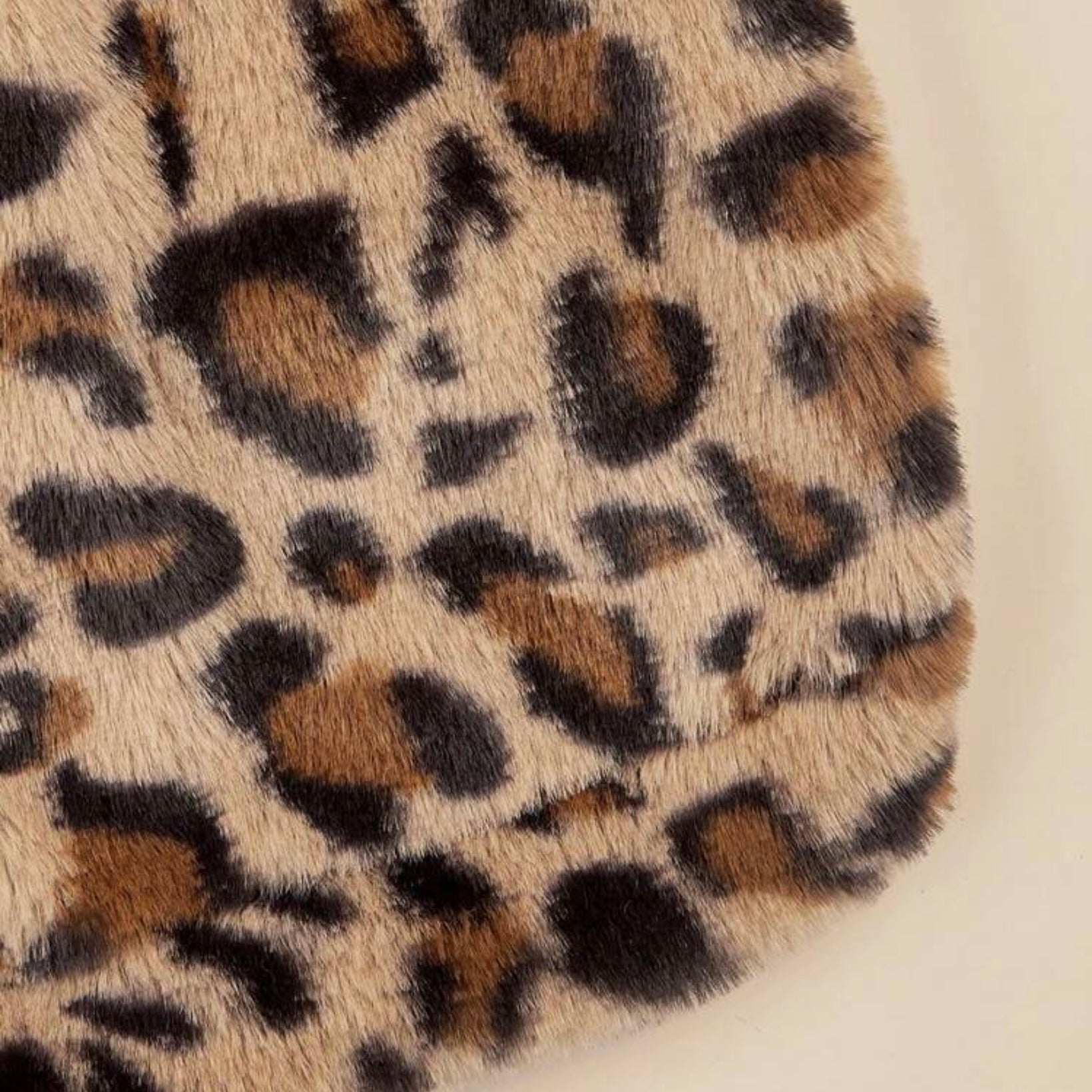 Close-up detail of the soft faux fur leopard print fabric of a dog hoodie.