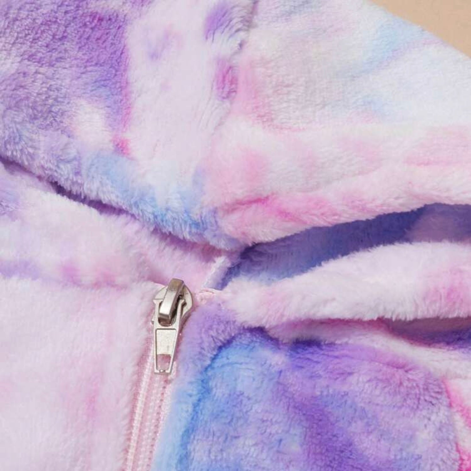 Close-up of the zipper and soft fabric texture on a pastel tie-dye dog hoodie jacket.