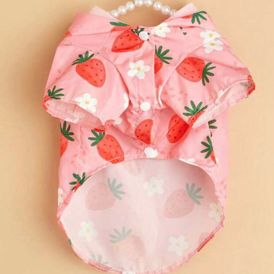 Front view of a pink dog raincoat with strawberry and flower pattern, showing snap button closure, displayed on a hanger.