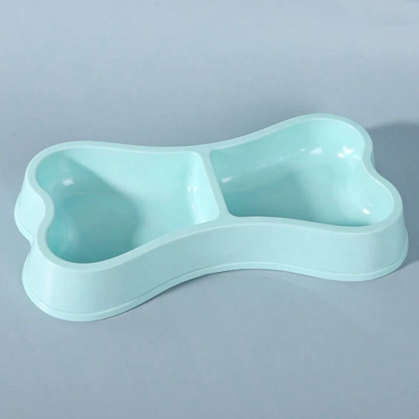 Close-up of a blue bone-shaped double dog bowl on a light blue background.