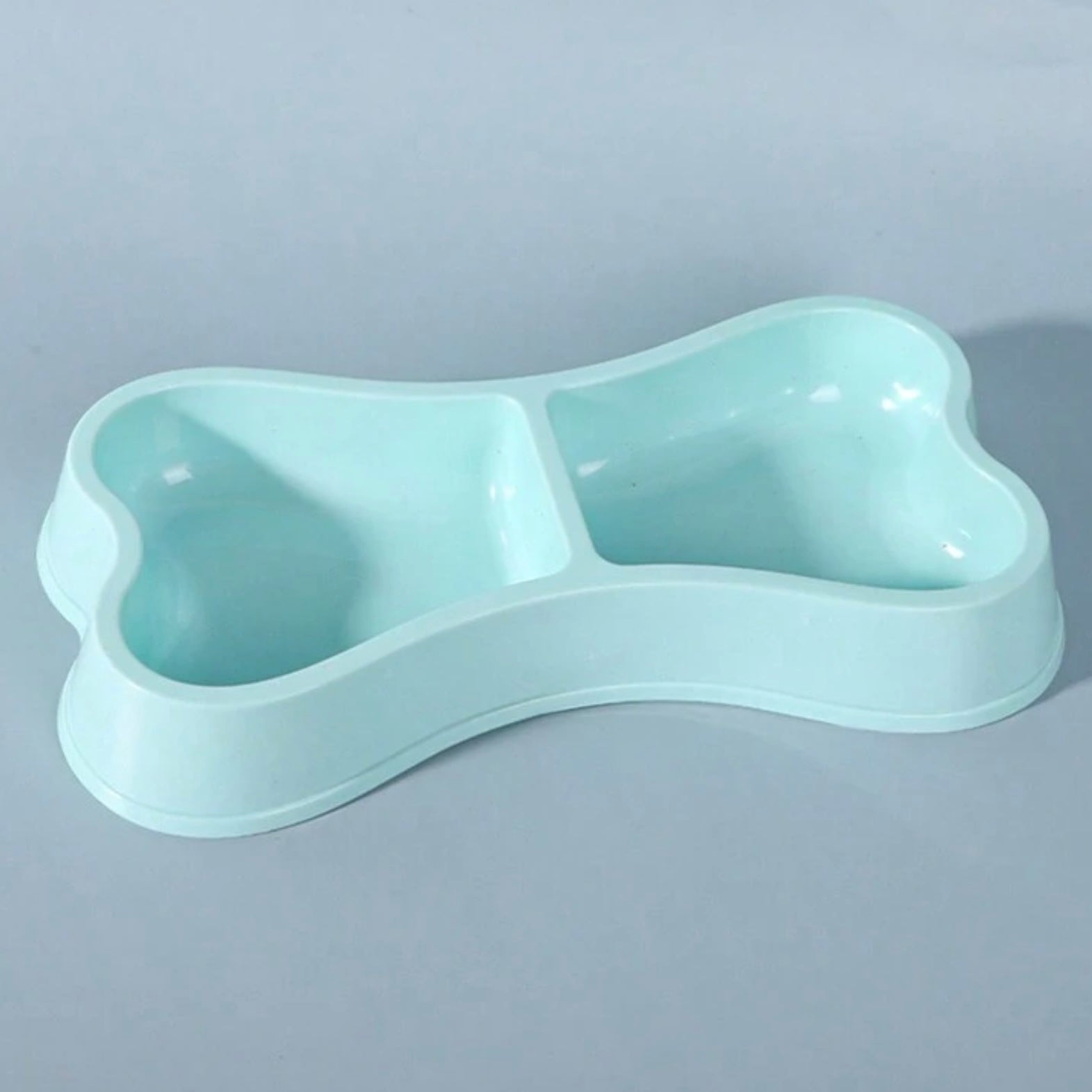 Close-up of a blue bone-shaped double dog bowl on a light blue background.