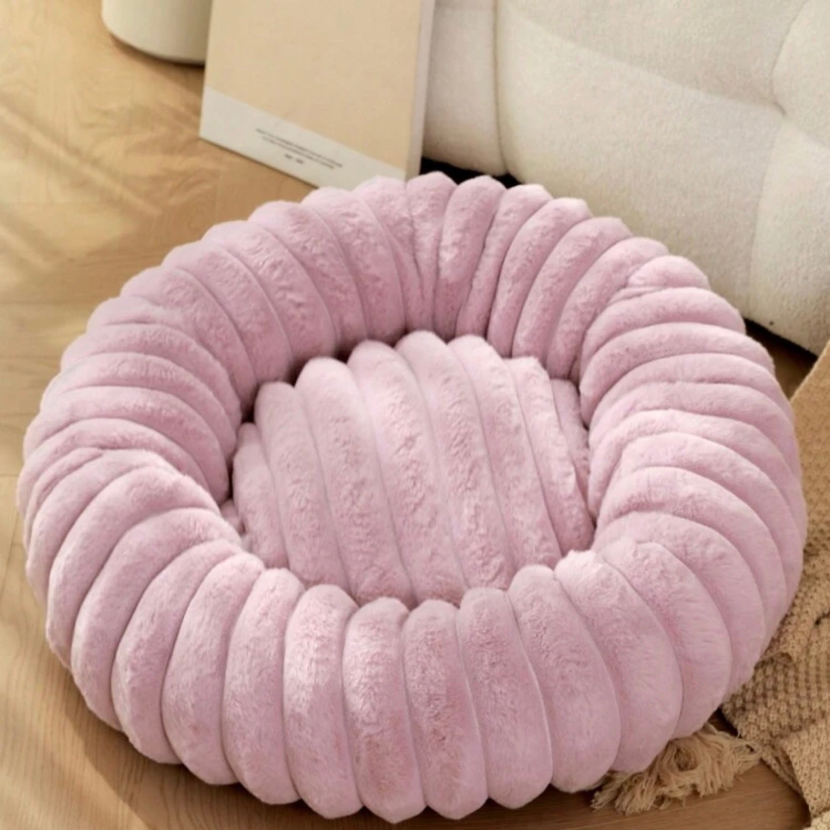 Plush ribbed donut dog bed in lilac placed indoors.