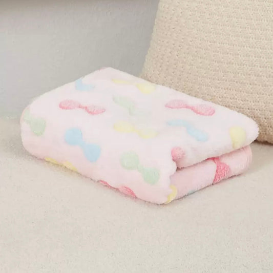 Soft dog blanket featuring pink, blue, yellow, and green bows, neatly folded.