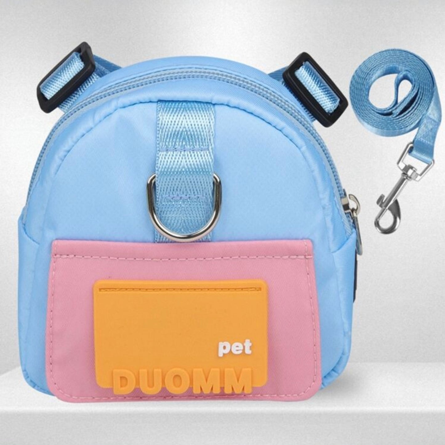 Light blue and pink dog backpack with an orange  patch labeled shown with a matching blue leash on a white background.
