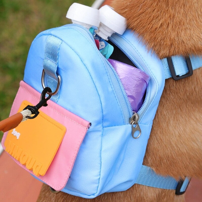 Side view of a light blue and pink dog backpack with an orange patch, worn by a brown dog, showing the backpack unzipped and filled with pet supplies.