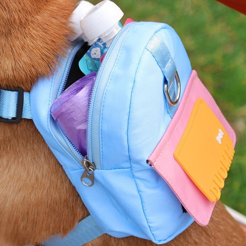Side view of a light blue and pink dog backpack with an orange patch, worn by a brown dog, showing the backpack unzipped and filled with pet supplies.