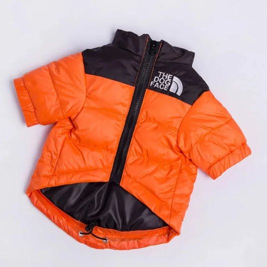 Orange and black puffer dog jacket with "The Dog Face" logo, shown flat with the zipper open and drawstring hem visible on a white background.