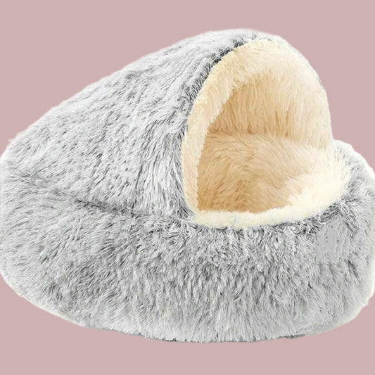 Gray and cream plush dog cave bed with a covered dome design on a pink background.