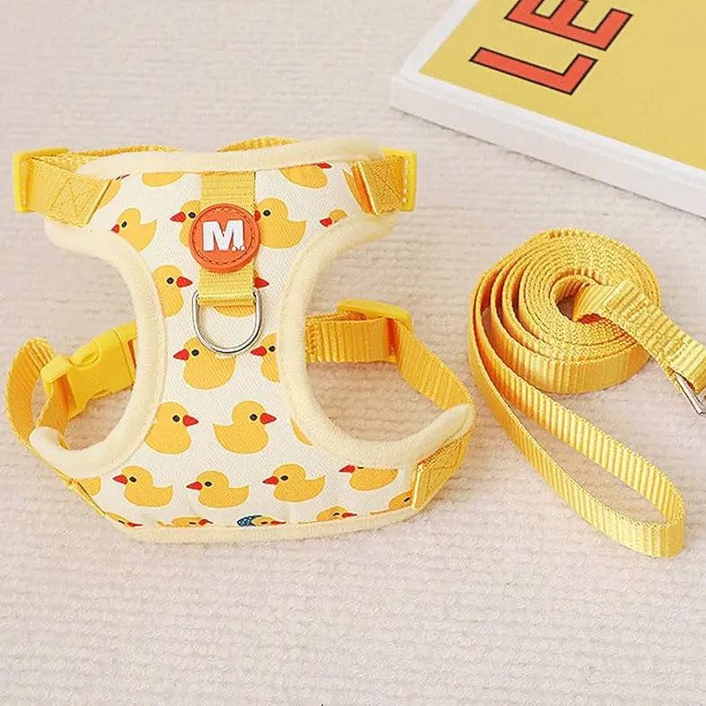 Yellow dog harness with duck pattern and matching yellow leash, displayed on a light surface.