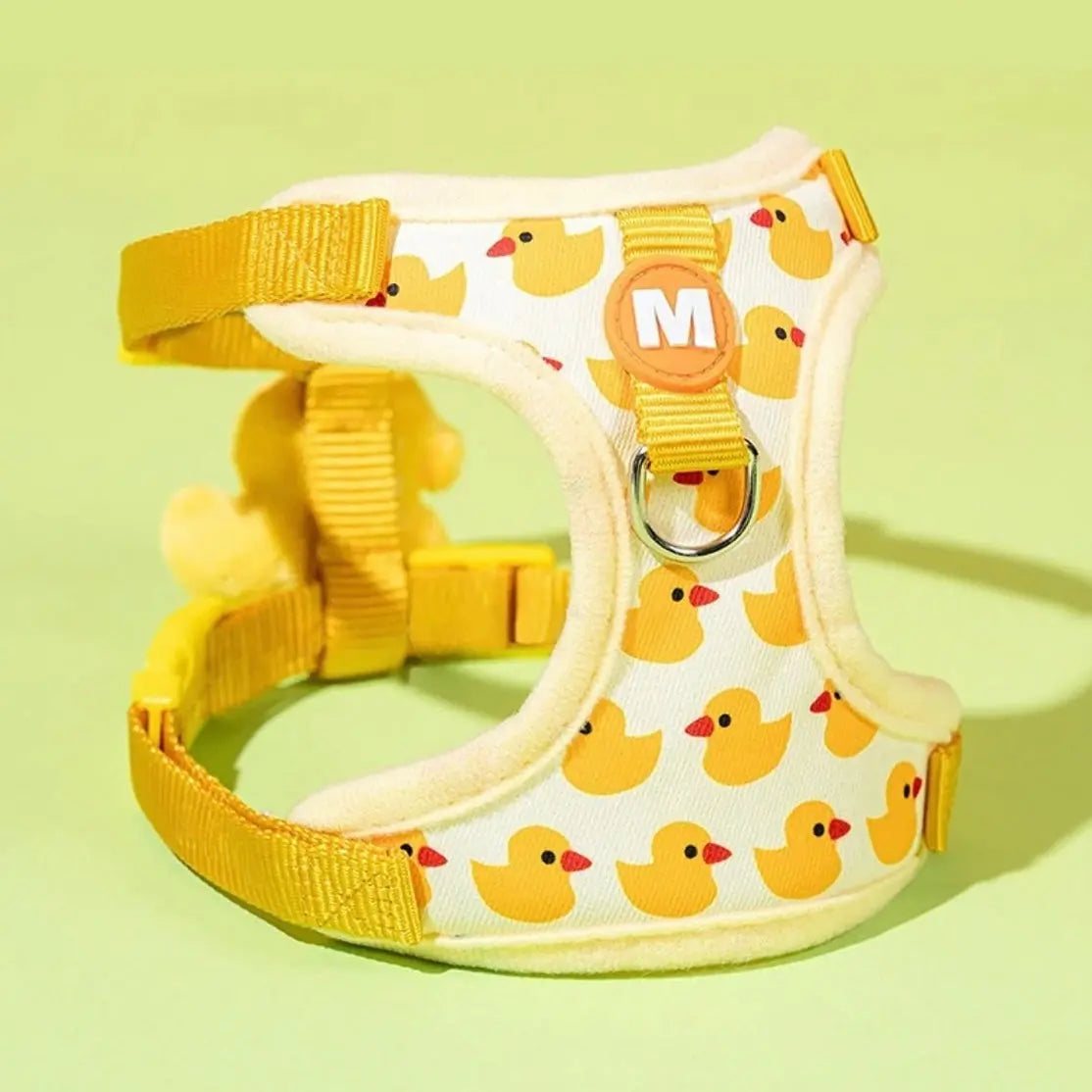 Yellow dog harness with duck pattern, size medium, displayed on a green background.