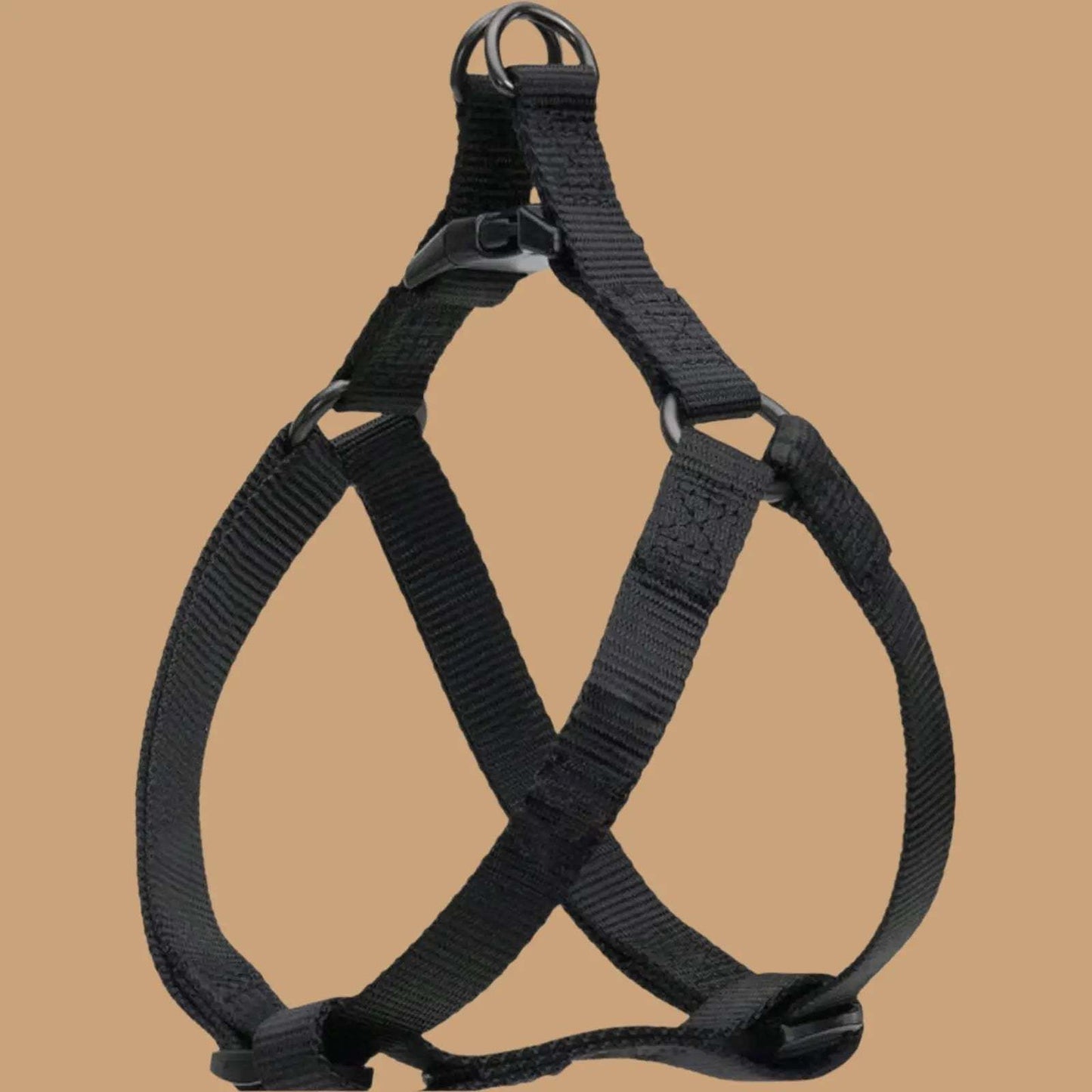 Black adjustable step in dog harness with plastic buckles and metal rings, displayed against a plain beige background.