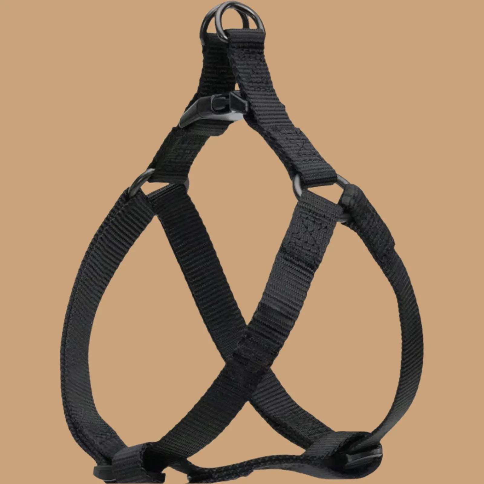 Black adjustable step in dog harness with plastic buckles and metal rings, displayed against a plain beige background.
