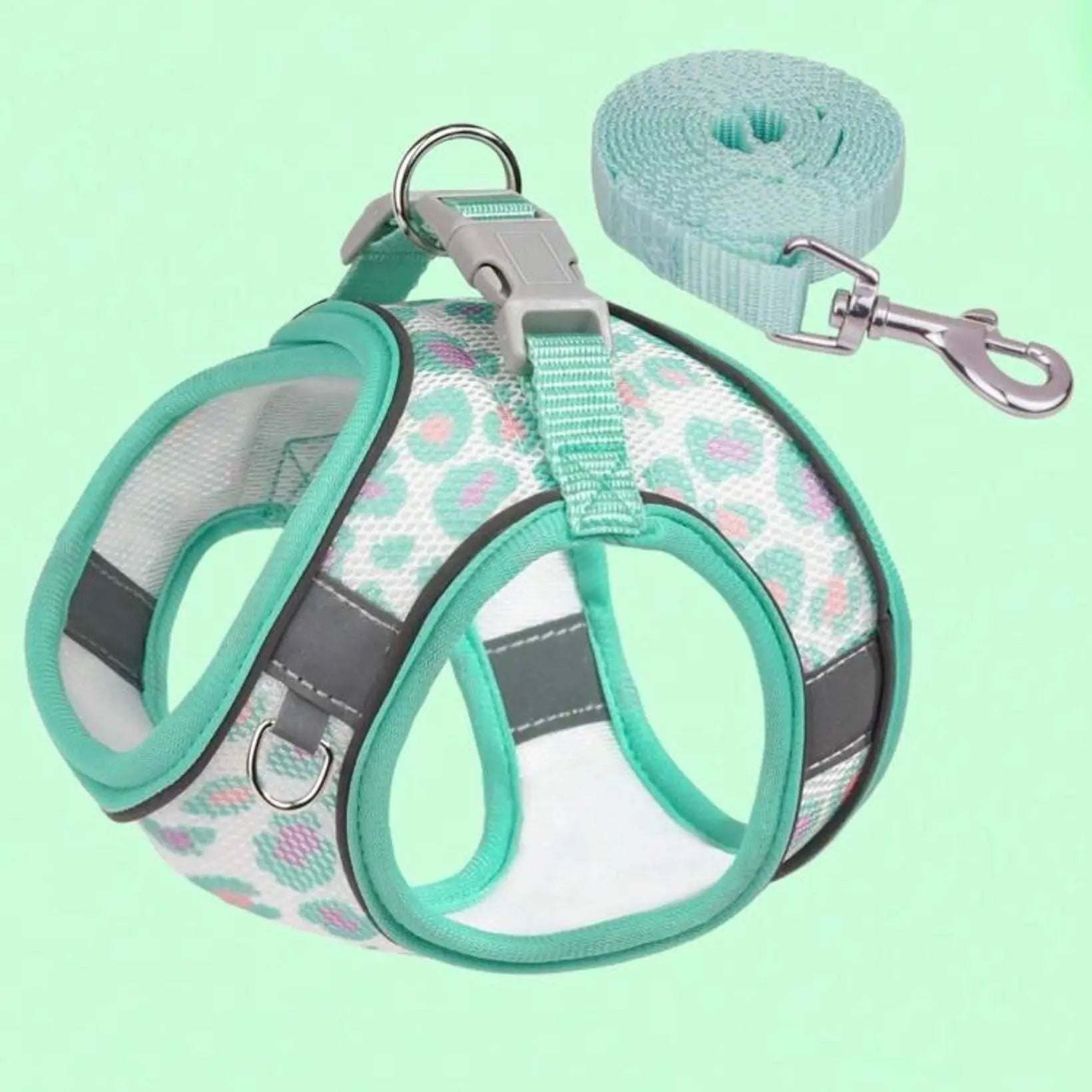 A teal and white dog harness with a matching teal leash, featuring a colorful leopard print pattern and reflective strips, displayed on a light green background.