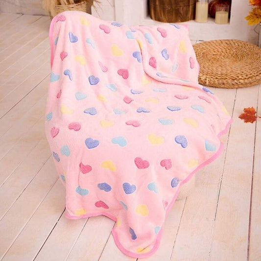 Pink dog blanket with colorful heart patterns draped over a chair in a cozy living room.