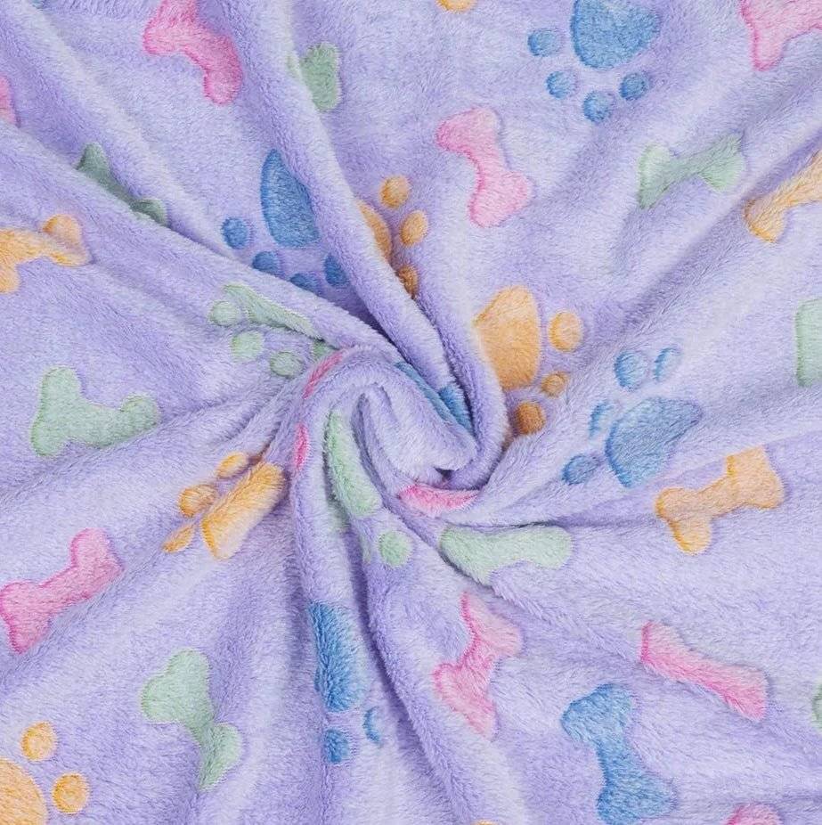 Lilac dog blanket with colorful paw prints and bone patterns, shown in a twisted display