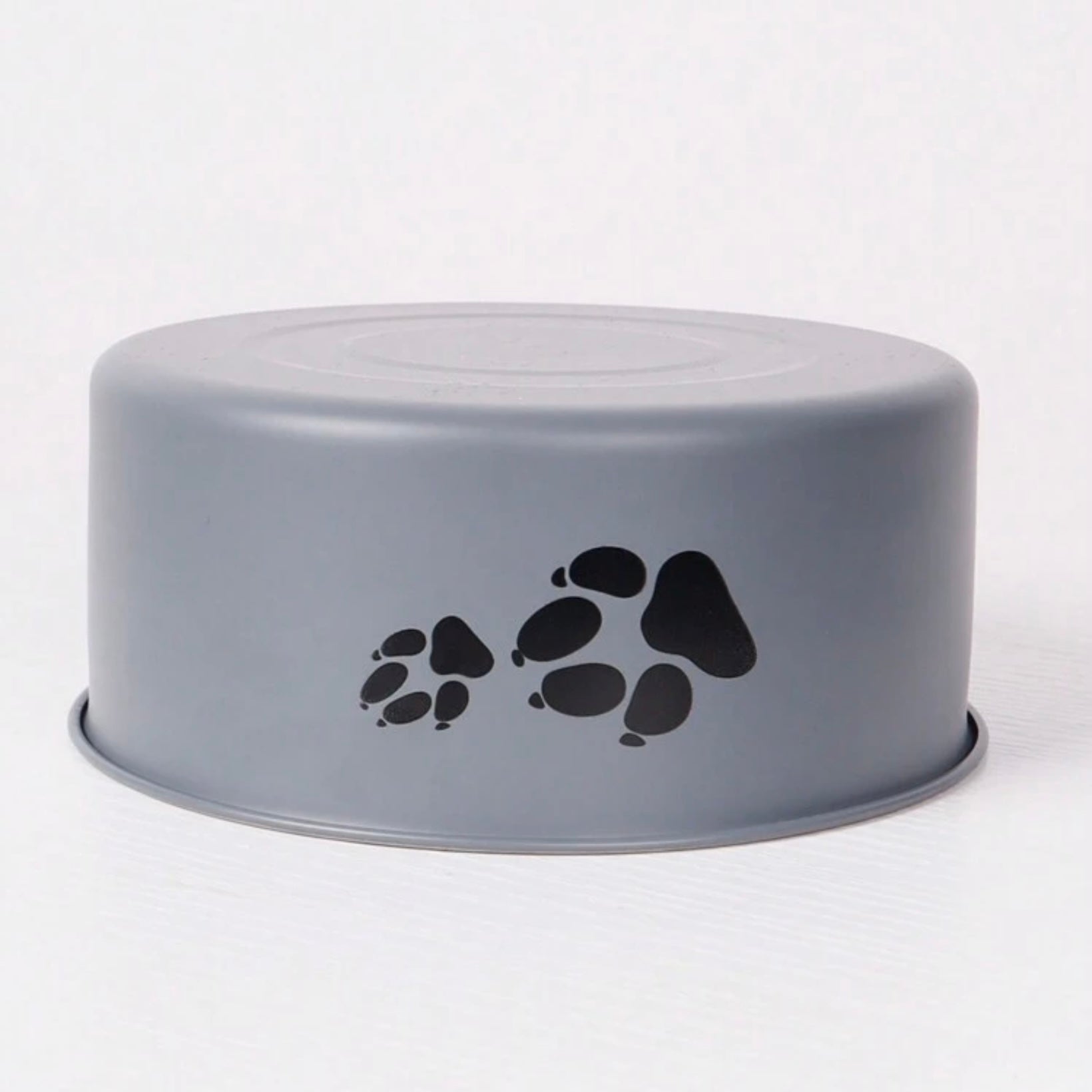 Upside-down gray dog bowl with black paw prints on the side, displayed on a plain background.