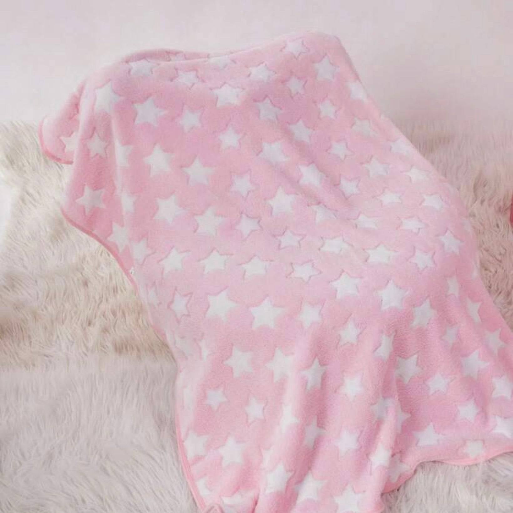 Pink dog blanket with white stars draped over an object, on a soft cream rug.
